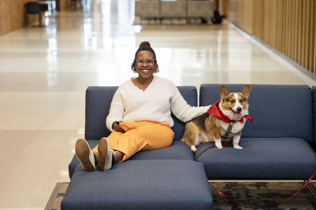 student sitting with therapy dog on a couch while smiling at camera
