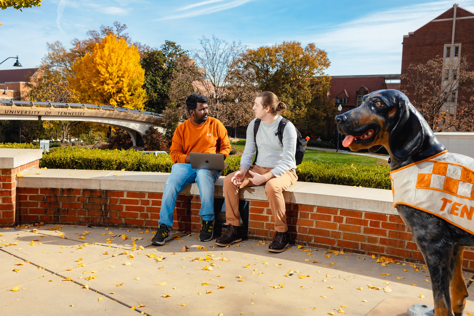 two social work students sitting outside Strong Hall with Smokey dog in foreground 