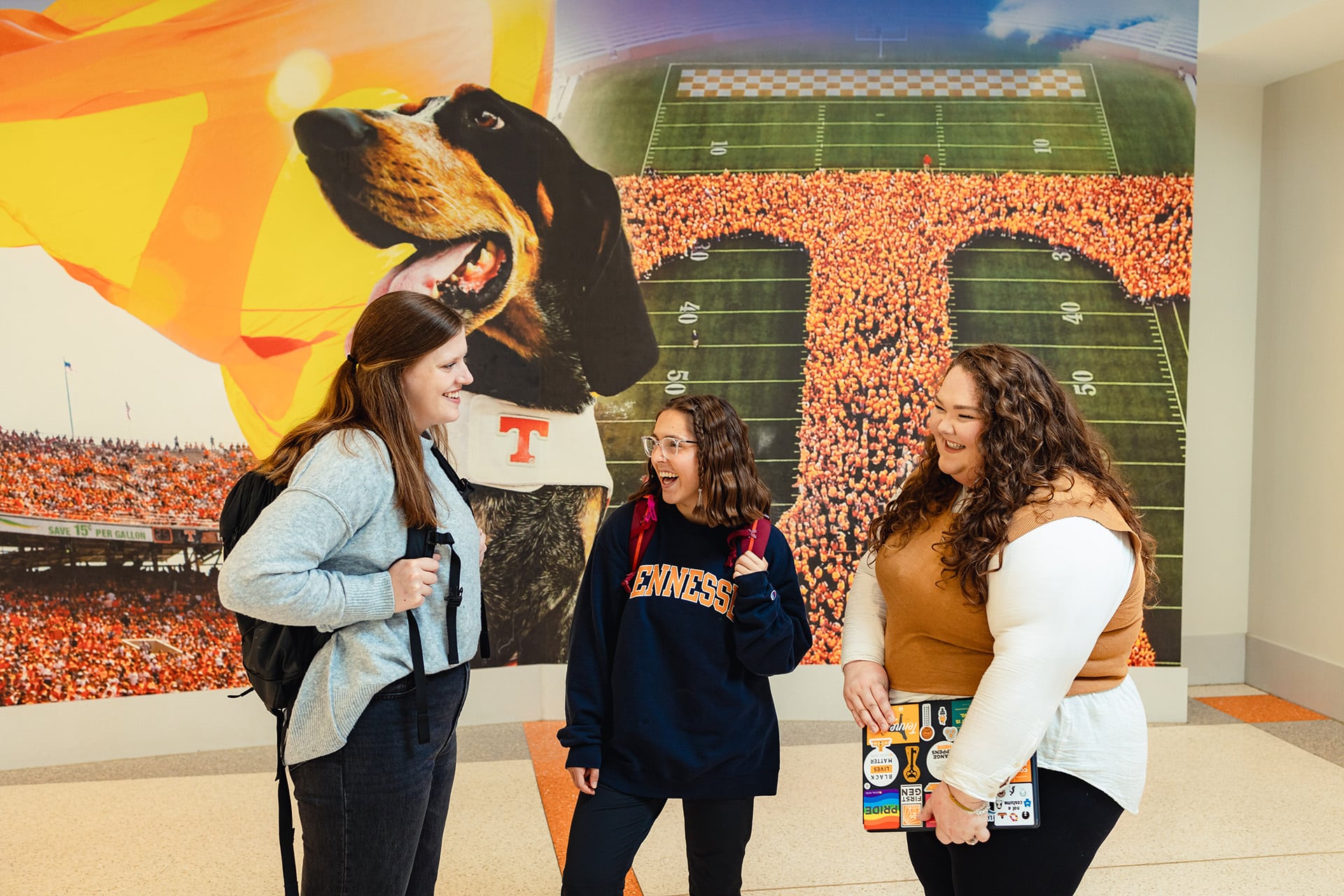 three social work students standing in front of mural of Smokey in the University of tennessee student union