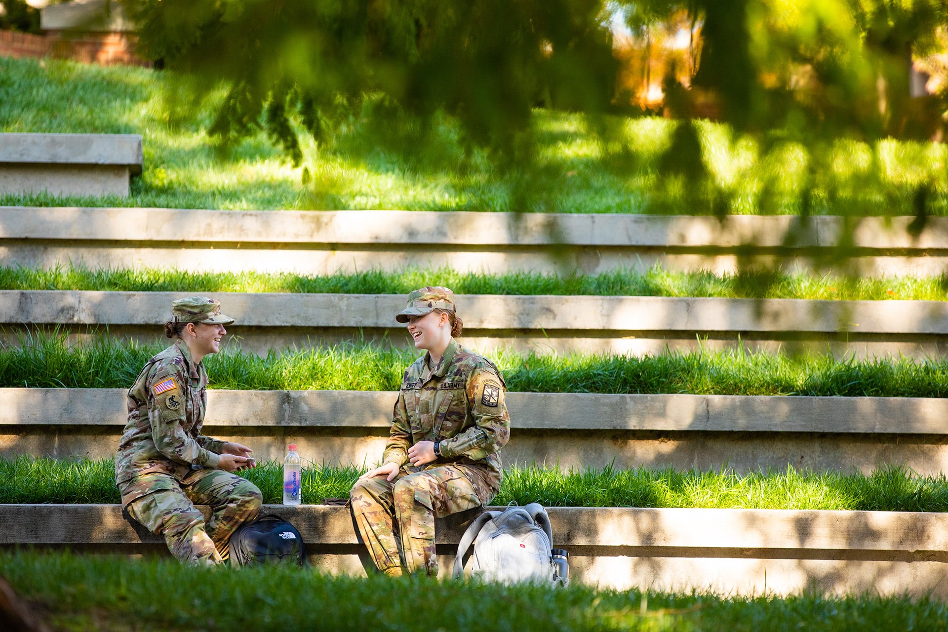 	Two Army ROTC students laugh while visiting at the HSS Amphitheater 