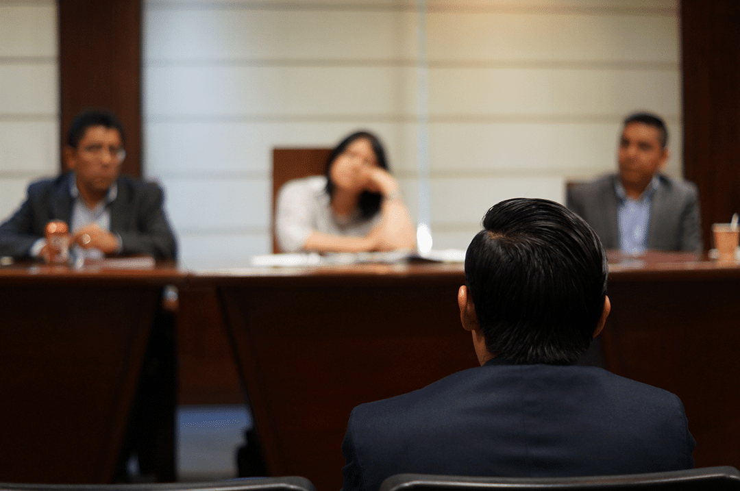 Out of focus view of a courtroom, with the back of lawyers seen in the foreground