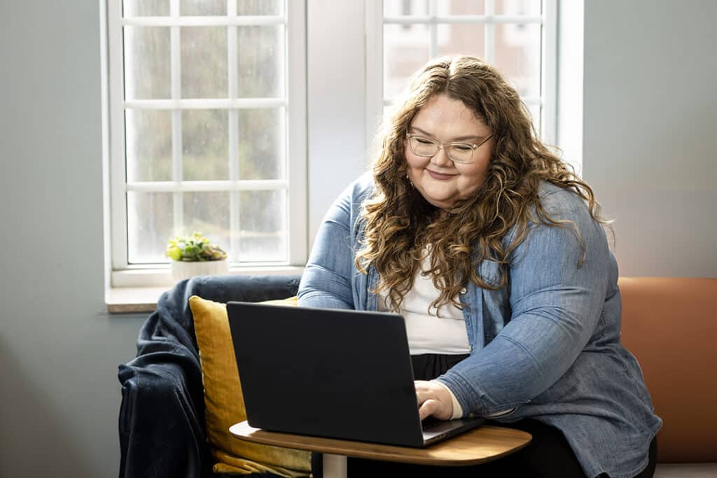 Cat Steele typing on laptop in dorm