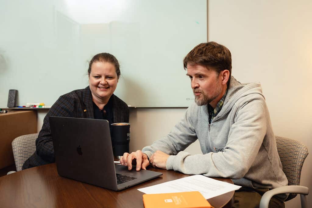 Deidre Ford and Nathan First from SWORPS looking over research stats on a laptop