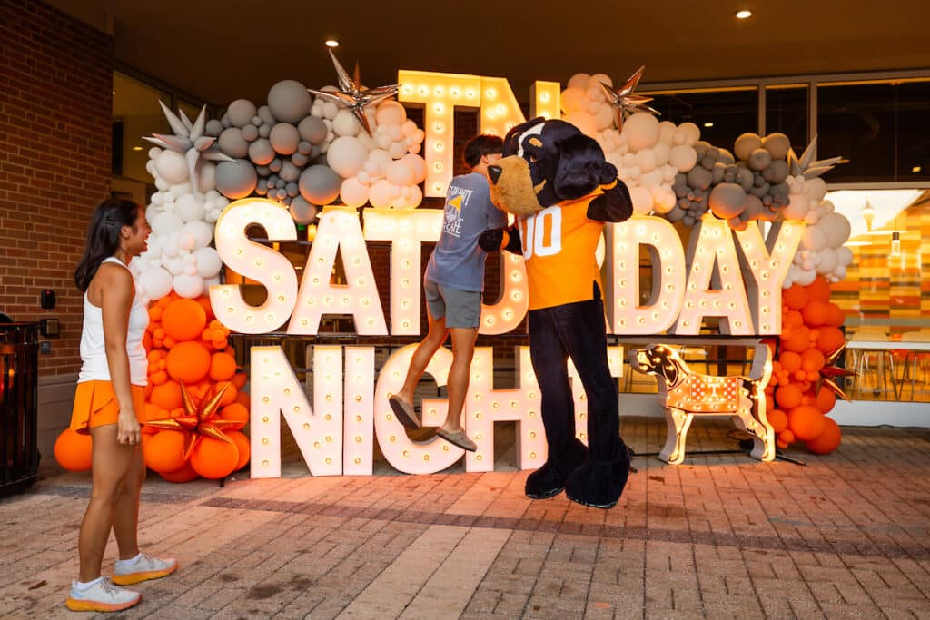 Smokey jumps to bump with a student at the Student Union during a Tennessee Saturday Night by the Division of Student Life