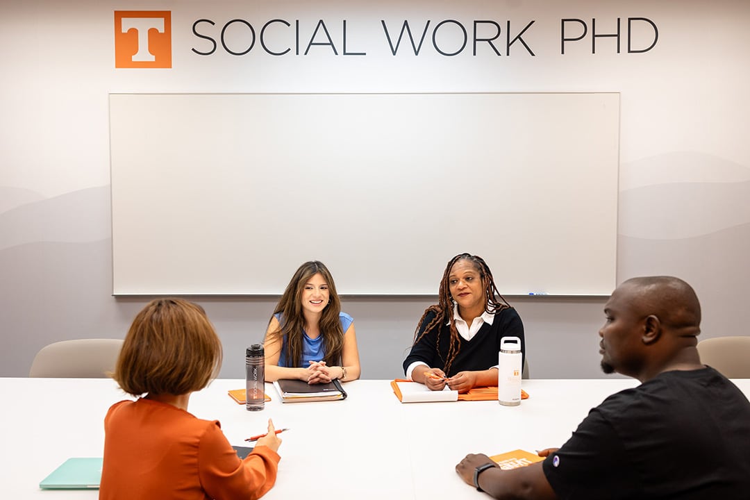 four phd students sitting in conference room chatting