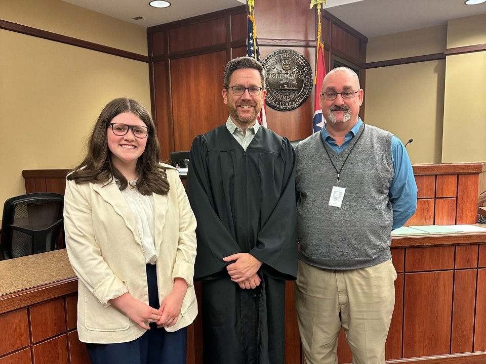 Megan Riedinger standing with judge and forensic social worker in court room