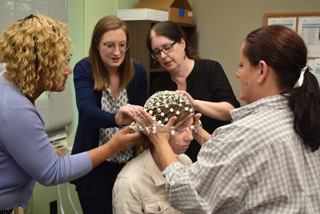 four female social work researchers applying EEG to female participants head