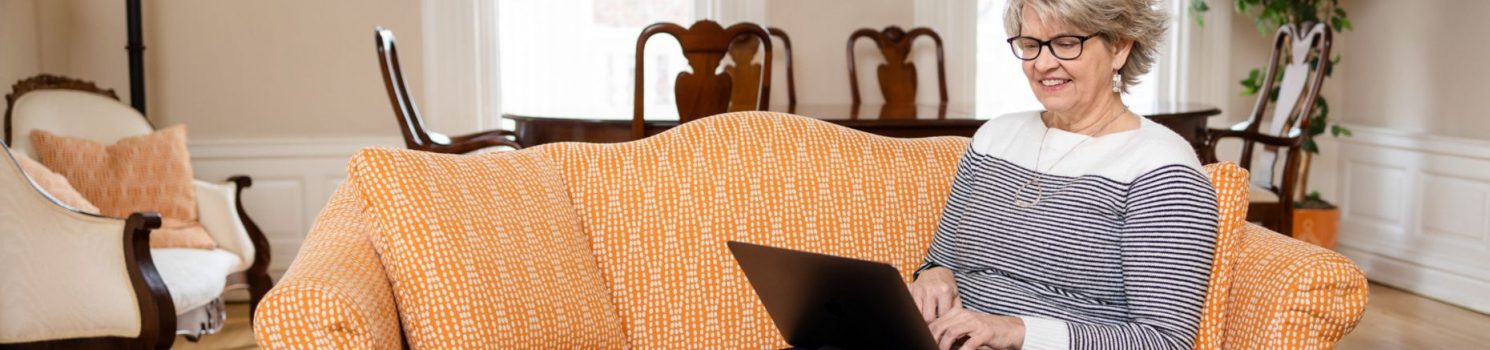 DSW student sitting on orange couch working on laptop