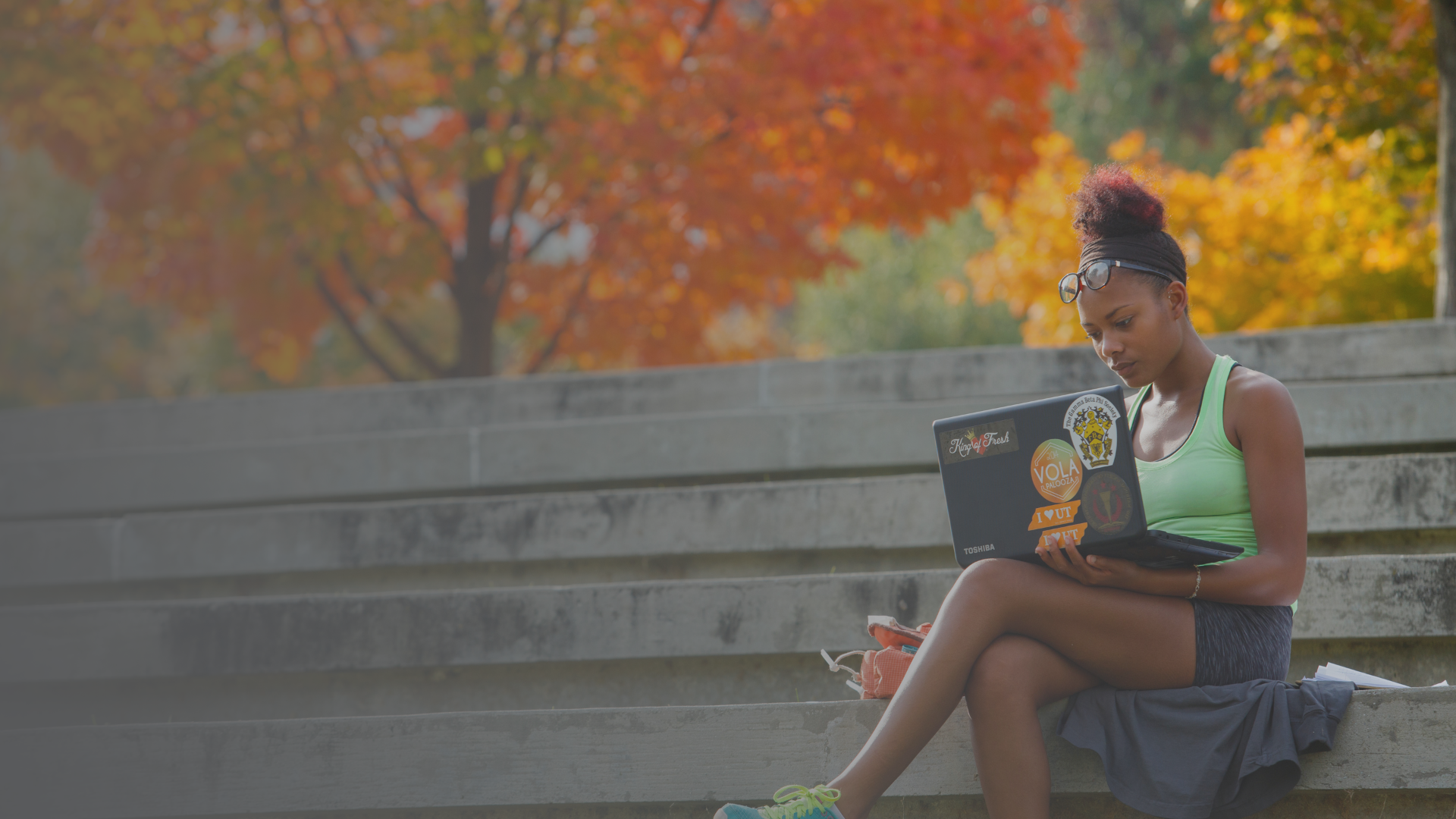 female black student wearing green top studying on laptop outside on University of Tennessee campus